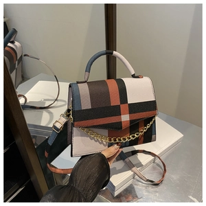 Close-up of structured geometric color-block handbag with gold chain detail and top handle