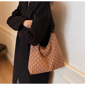 Close-up of a brown textured hobo bag with white dot patterns and thin leather straps