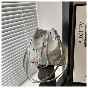 Détail du sac seau plissé gris avec papillons métalliques et cordon en chaîne argentée