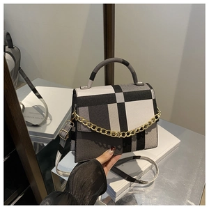Close-up of contrast patchwork handbag with gold chain detail and textured fabric