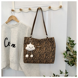 Detail of leopard print tote bag with brown leather tag and cloud plush charm