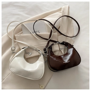 Detail of crescent shoulder bags with clover charm and glossy patent leather finish