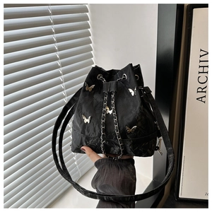 Détail du sac seau noir à cordon avec papillons métalliques et texture gaufrée