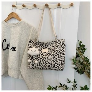 Detail of leopard print canvas tote bag featuring white straps and cloud plush charm decoration