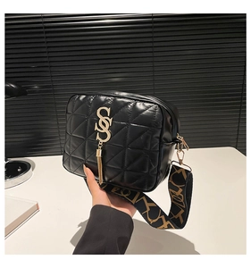Detail of black quilted crossbody bag featuring golden SOS logo and metal tassel