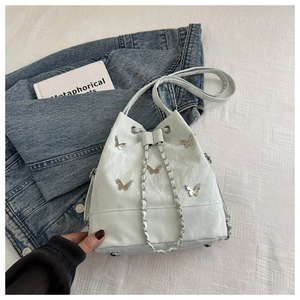 Détail du sac seau vert menthe avec ornements papillon argentés et cordon en chaîne