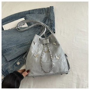 Détail du sac seau papillon gris avec texture plissée et chaîne en métal argenté