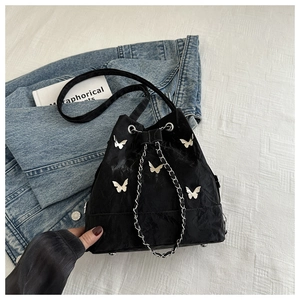 Détail d'un sac seau noir plissé avec breloques papillon argentées et chaîne en métal