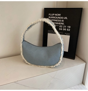 Détail du sac demi-lune en denim bleu clair avec des bords décoratifs à franges blanches