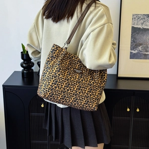 Chic leopard print canvas tote bag with leather straps worn by model in a casual setting