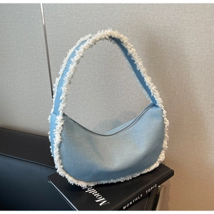 Détail du sac demi-lune en jean bleu clair avec garniture à franges blanches et zip