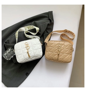 Detail of quilted leather crossbody bags with golden logo tassels and wide printed straps