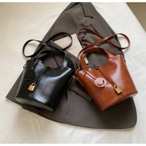 Détail de sacs seaux minimalistes en similicuir noir et marron avec petit cadenas doré