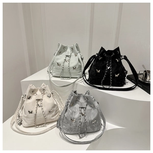 Détail de sacs seaux papillon en vert menthe, noir, blanc et gris avec des chaînes