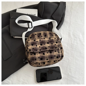 Detail of plaid crossbody bag with heart print and adjustable white canvas strap