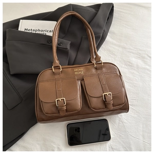 Brown leather bowling bag featuring cargo pockets and smartphone for size comparison