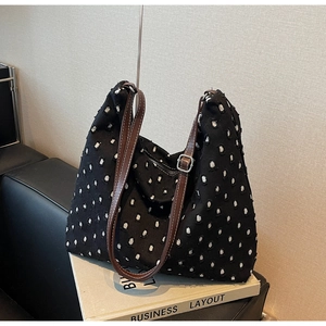 Detail of canvas tote bag with white textured polka dots and brown faux leather straps