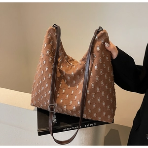 Detail of brown hobo tote bag featuring frayed canvas texture and adjustable leather strap