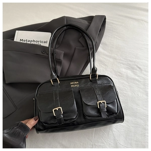 Detail of black litchi pattern PU leather tote with gold AKOBIA PEOPLE logo text