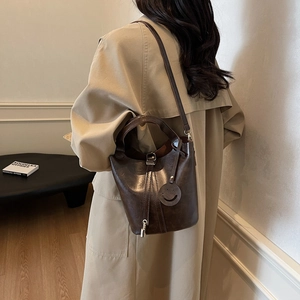 Sac seau rétro marron foncé avec poignée et bandoulière porté par un mannequin