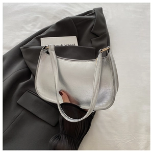 Detailed texture of silver metallic crescent hobo bag resting on a black blazer