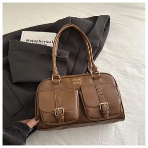 Detail of brown faux leather handbag featuring dual front pockets and gold hardware