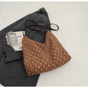 Detailed texture of caramel brown pleated shoulder bag on grey suit background