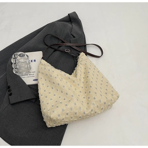 Detail of beige hobo bag with geometric texture and adjustable brown leather strap