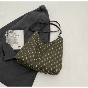 Close-up of green polka dot hobo bag with frayed fabric and brown leather strap