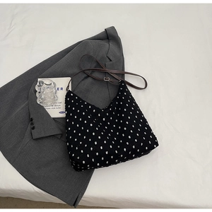 Detail of black polka dot hobo bag with tufted texture and brown leather strap
