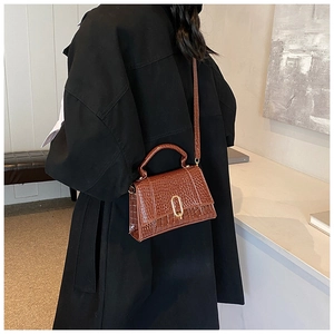 Détail d'un sac à main en cuir marron à motif crocodile porté en bandoulière élégante