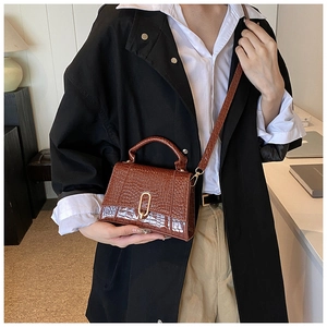Détail du sac à main en similicuir marron foncé avec motif croco et boucle dorée
