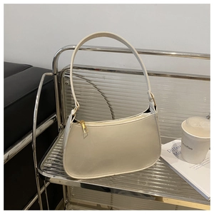 Macro shot of white leather crescent shoulder bag with golden zipper and sleek texture