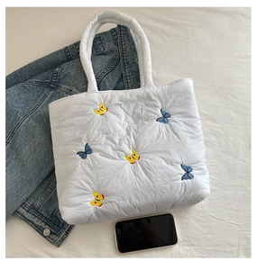 Detailansicht der weißen gesteppten Nylon-Tasche mit blau-gelber Schmetterlingsstickerei
