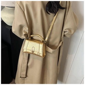 Détail du sac à main doré effet crocodile porté avec un trench-coat kaki élégant
