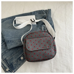 Detail of grey nylon bag with red heart print and white adjustable shoulder strap