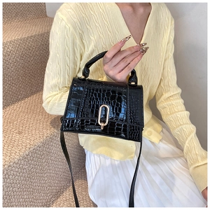 Détail du sac bandoulière noir motif crocodile avec un fermoir en métal doré brillant