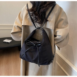 Detail der minimalistischen schwarzen Zugbandtasche mit Lederschleife auf Khaki Trenchcoat