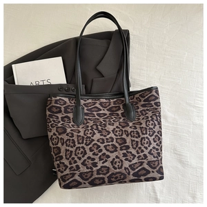 Dettaglio della borsa tote con stampa leopardata e manici neri su sfondo bianco