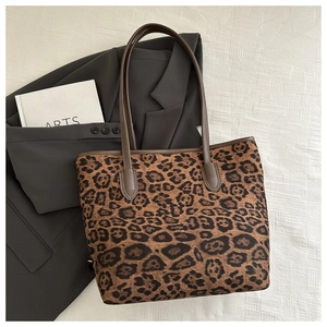 Dettaglio della borsa tote leopardata con manici in pelle marrone su tessuto bianco