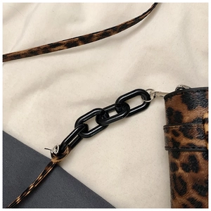 Detail of leopard print crossbody bag featuring black chunky chain and silver hardware