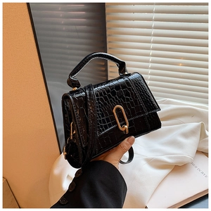 Vue détaillée de la texture crocodile noire et de la boucle en métal doré sur le sac à main