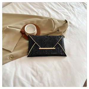 Flat lay of a black snakeskin pattern envelope clutch bag with gold metallic trim
