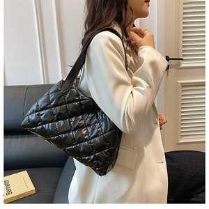 Detailed side view of a black quilted puffer tote bag on a model in a stylish home setting