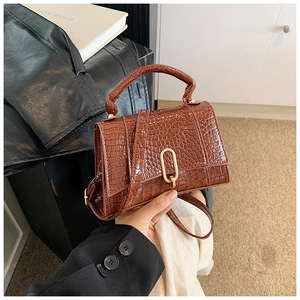 Détail d'un sac à main marron à motif crocodile avec fermoir doré et bandoulière