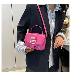 Detail of rose pink crossbody bag with a large gold metal buckle on leather texture