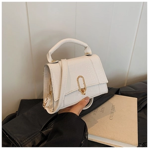 Gros plan du sac à main blanc motif crocodile avec fermoir doré et poignée chic