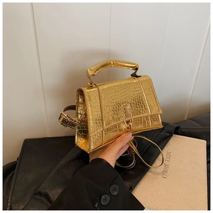 Gros plan du sac doré texture crocodile avec boucle métallique et poignée chic