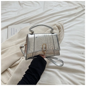 Détail du sac à main argenté effet crocodile avec boucle dorée en U et texture métallique