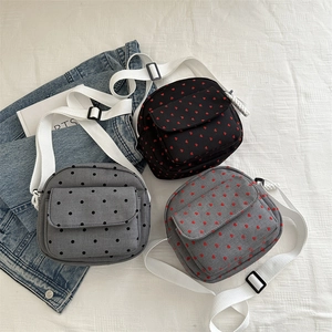 Three nylon crossbody bags with heart prints and adjustable straps on white background